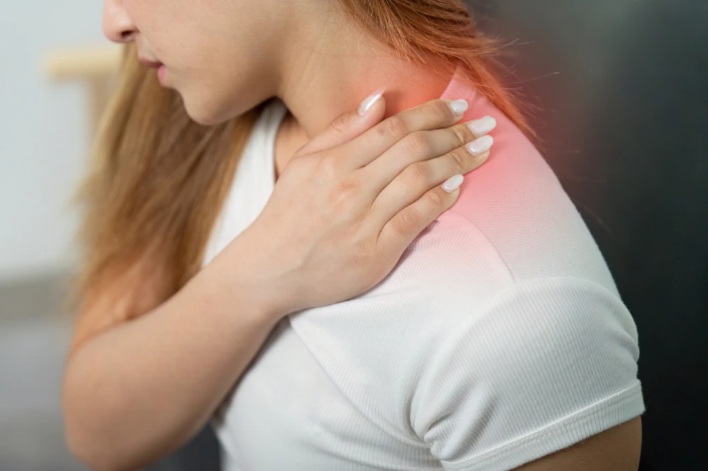 Woman holding the back of her neck with visible discomfort, illustrating cervical neck pain requiring neurological evaluation.