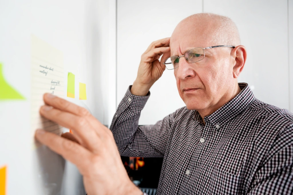 Older adult experiencing memory difficulties while looking at reminder notes, illustrating symptoms that may require neurological evaluation.