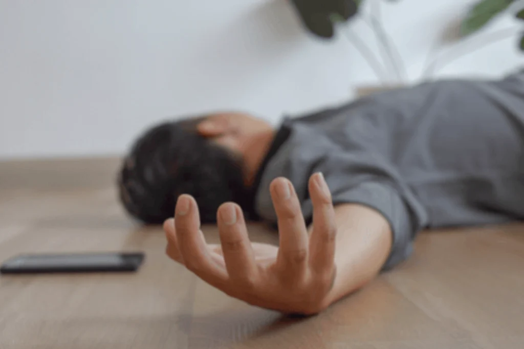Person lying unconscious on the floor, illustrating a seizure emergency requiring immediate neurological evaluation and medical care.