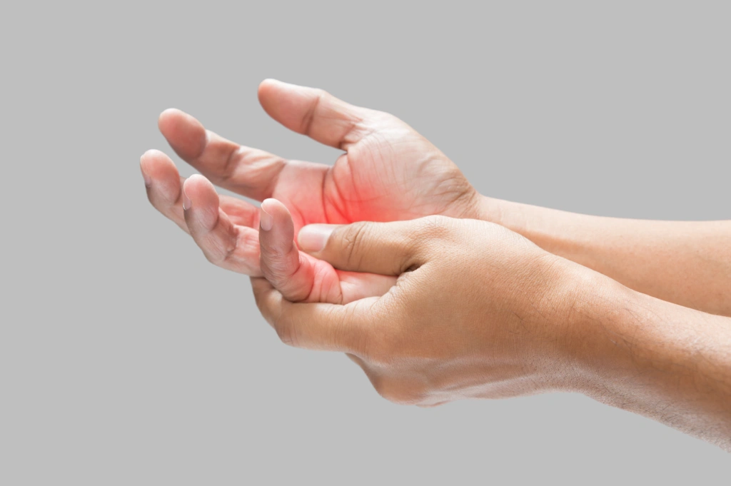 Person holding a hand with visible discomfort, illustrating tremor symptoms that may require neurological evaluation.