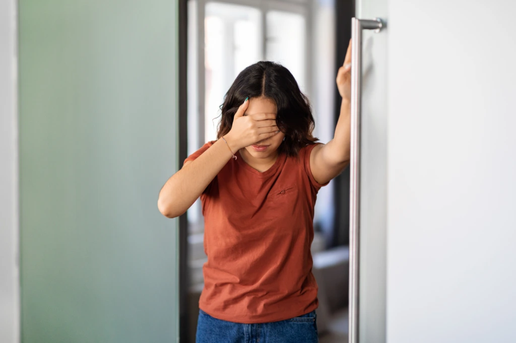 Woman experiencing dizziness while holding a support rail, illustrating symptoms of vertigo requiring neurological evaluation.